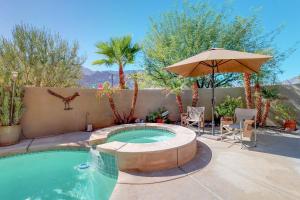 a swimming pool with an umbrella and a table and chairs at Lovely La Quinta Permit# 66318 in La Quinta