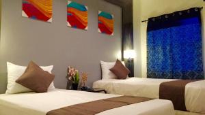 two beds in a hotel room with paintings on the wall at My Dream Place Hotel - Near Robinsons Mall in Butuan