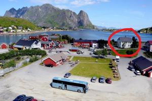 un autobús estacionado frente a un pueblo con un círculo rojo en Det Gamle Hotellet Guesthouse, en Reine