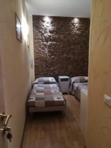 a bedroom with two beds and a stone wall at B&B In Piazza in Rome
