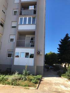 a tall white building with a balcony at Apartments Mikulić in Zadar