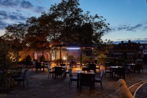 a patio with tables and chairs and a dog at Sir Christopher Wren Hotel in Windsor