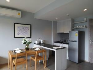 a kitchen with a table and a refrigerator at 23 องศา คอนโด เขาใหญ่ in Nakhon Ratchasima