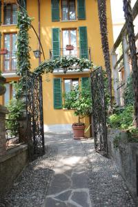 um portão aberto que leva a um edifício amarelo com vasos de plantas em Hotel Centrale Bellagio em Bellagio