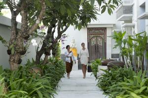 two women walking down a walkway in front of a building at The Village Home in Sanur