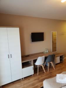 a bedroom with a desk with a television and two chairs at Hotel Pod Strzechą in Kielce