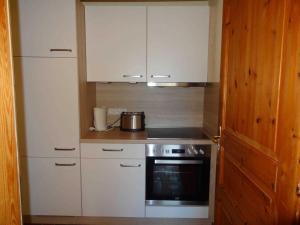 a small kitchen with white cabinets and a stove at Heidelberg Viola in Neustadt in Holstein