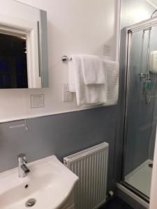 a bathroom with a shower, sink, and mirror at Cullen Bay Hotel in Cullen