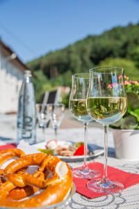 - une table avec deux verres de vin et une assiette de bretzels dans l'établissement Hotel Restaurant Haus Waldesruh, à Eppenbrunn