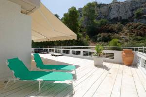 a deck with two chairs and an umbrella at Sea View Dreamy Penthouse in Vouliagmeni in Athens