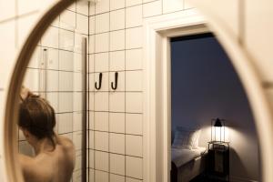 a woman standing in a bathroom looking into a mirror at Stilleben Hotell in Åmot