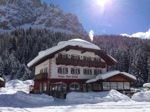 a building covered in snow with a mountain in the background at Rifugio Monti Pallidi in Canazei