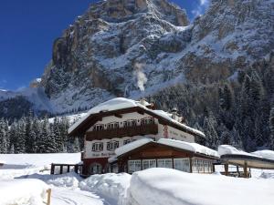 a house covered in snow in front of a mountain at Rifugio Monti Pallidi in Canazei