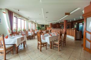 a restaurant with white tables and chairs and windows at Bonanza Pensiune & Restaurant in Cluj-Napoca