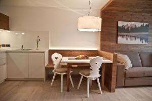 Il comprend une cuisine et un salon avec une table et des chaises. dans l'établissement Ariston Dolomiti Residence, à Dobbiaco