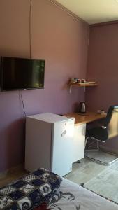 a room with a desk and a television on the wall at Otentik guesthouse in Mbabane