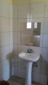 uma casa de banho com um lavatório branco e um espelho. em Otentik guesthouse em Mbabane