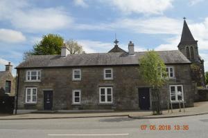 MultyfarnhamThe Stone House, Multyfarnham的一座古老的砖砌建筑,后面有一座教堂