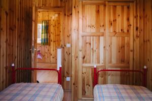 1 Schlafzimmer mit 2 Betten und einer Holzwand in der Unterkunft Camping Rural Ria de Arosa 2 in Ribeira + 46 Fotos