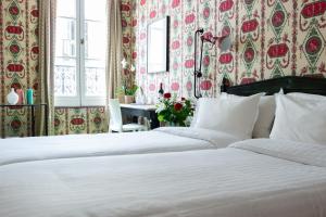 two beds in a bedroom with floral wallpaper at Prince de Conde in Paris