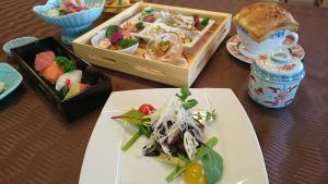 una mesa cubierta con platos de comida y tazones de comida en OkutsuHotSpa IkedayaKajikaen, en Kagamino
