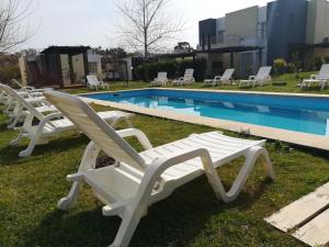 a row of white lounge chairs next to a swimming pool at las martinas apart 5 in Piriápolis