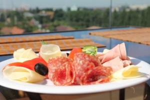 um prato de alimentos com carne e legumes sobre uma mesa em Pensiunea Puiu em Afumaţi