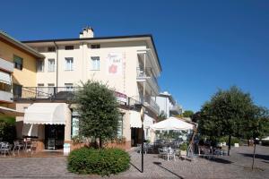 un edificio con tavoli e ombrelloni di fronte ad esso di Apart-Hotel la Rocchetta a Padenghe sul Garda