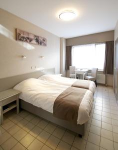 ein Hotelzimmer mit einem großen Bett und einem Schreibtisch in der Unterkunft Hotel De Golf in Bredene