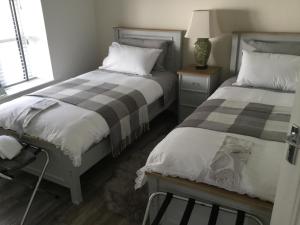 a bedroom with two beds and a table with a lamp at The Stone House, Multyfarnham in Multyfarnham