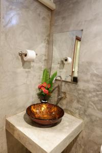 a sink in a bathroom with a mirror and flowers at โรงแรมโทนี่วิลเลจTony Hotel in Phatthalung +24 photos