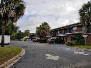 an empty parking lot with palm trees and a building at Palmetto Inn in Estill
