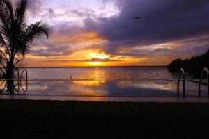 una puesta de sol sobre un cuerpo de agua con una palmera en Nico Lagoon Hotel en Negombo