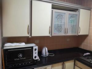a kitchen with a black counter top with a microwave at شقق الحي الايطالي in 6th Of October