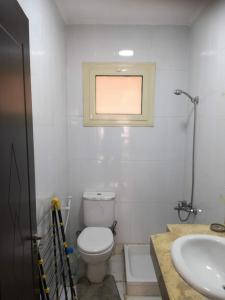 a bathroom with a toilet and a sink and a window at شقق الحي الايطالي in 6th Of October