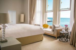 Un dormitorio con una cama grande y un sofá y ventanas. en The Chatsworth Hotel, en Eastbourne