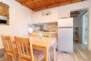 a kitchen with a wooden table and a refrigerator at Greenside Cottage Lumi in Vela Luka