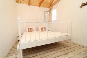 Cama blanca en habitación con suelo de madera en Greenside Cottage Lumi en Vela Luka