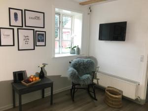 a room with a chair with a table and a tv at Hos Mette in Børkop