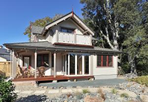 a small white house with a porch and balcony at Baywick Inn Bed & Breakfast in Nelson