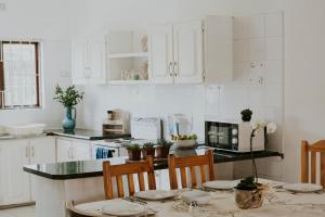 a kitchen with white cabinets and a table with chairs at Shelly Beach, Villa Albatross 2 in Shelly Beach