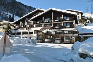 un edificio alberghiero con auto parcheggiate nella neve di Hotel Daneu Gaschurn a Gaschurn