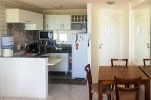 a kitchen with a table and a white refrigerator at Marina Bezerril - 304 Pontamares - O melhor de Natal in Natal