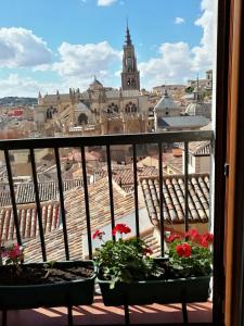 トレドにあるApartamento PRANA Junto al Alcázarの花の咲くバルコニーから市街の景色を望めます。