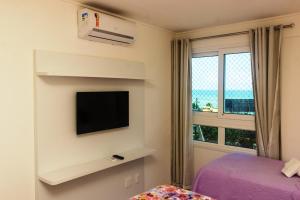 a bedroom with a bed and a tv and a window at Marina Bezerril - 304 Pontamares - Pertinho de tudo,mar e restaurantes in Natal