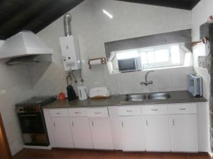 a small kitchen with white cabinets and a sink at Casa Dos Mosteiros in Mosteiros
