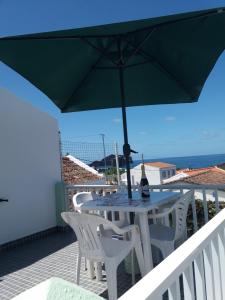 a table and chairs with an umbrella on a balcony at Casa Dos Mosteiros in Mosteiros