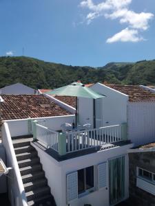 a white house with a balcony with an umbrella at Casa Dos Mosteiros in Mosteiros
