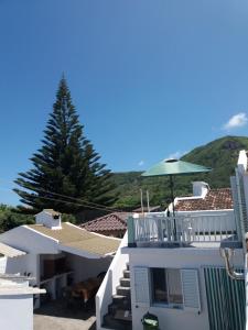 a white house with a green umbrella and a tree at Casa Dos Mosteiros in Mosteiros