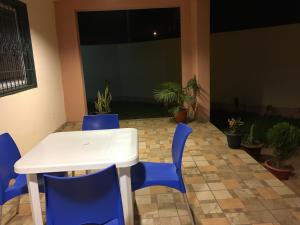 a white table and blue chairs in a room with plants at Residence AMAK in Ouagadougou